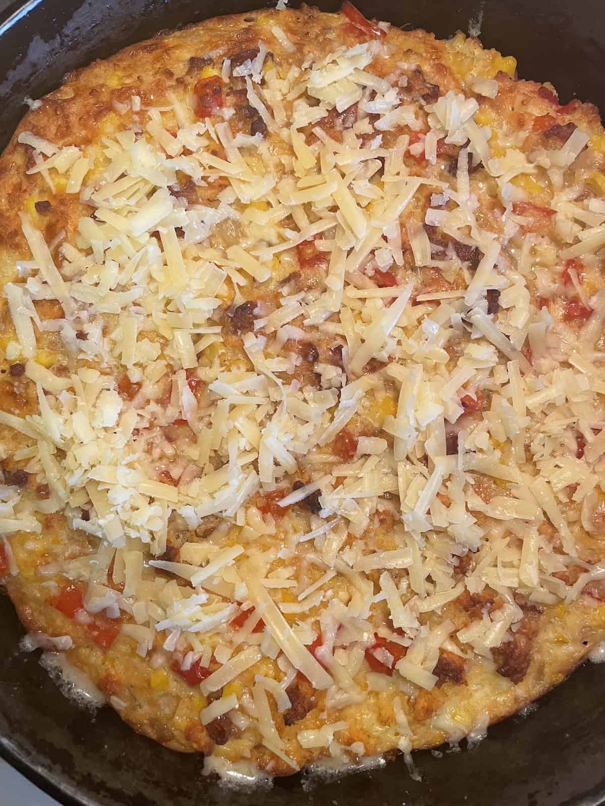 Corn bread pudding topping with cheese toward end of baking