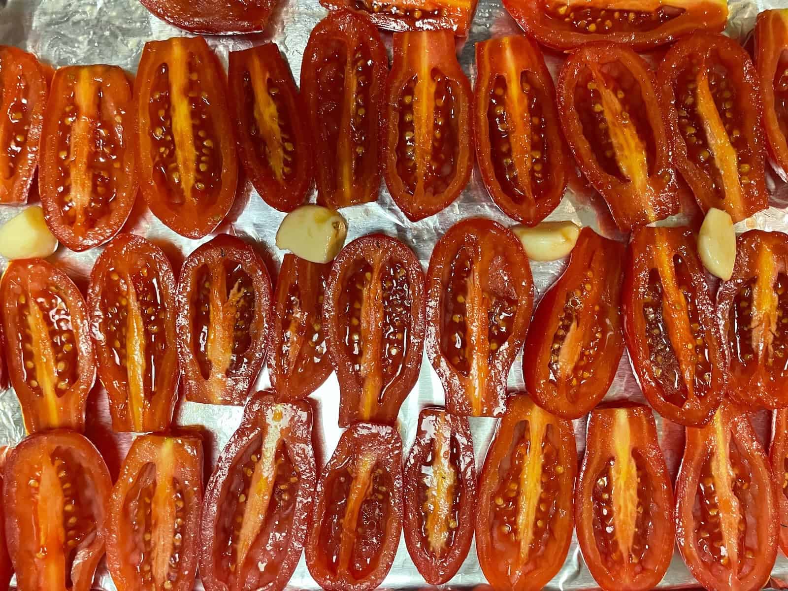 Creamy Roasted Tomato and Parmesan Soup -- tomato halves and garlic on a baking sheet