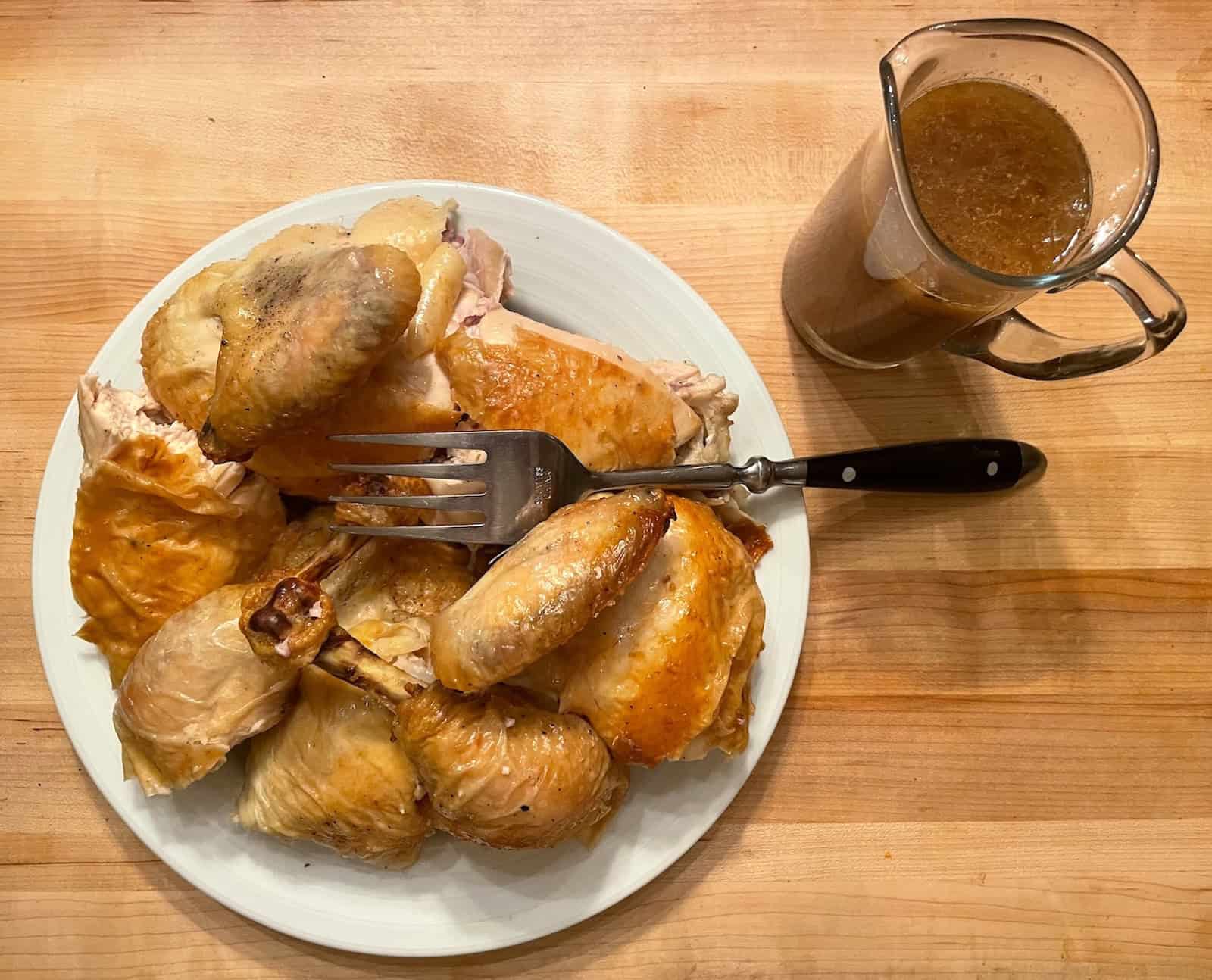 Lemon and Herb Roasted Chicken lead photo with chicken on a plate with sauce in a pitcher