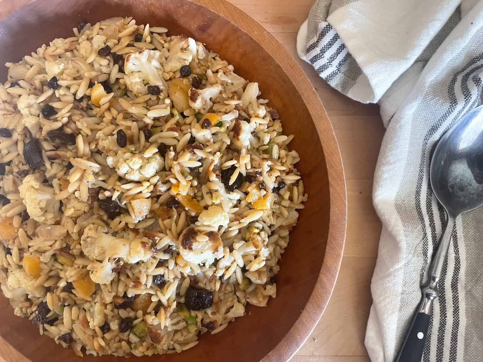 Orzo Salad with Roasted Cauliflower, Dried Fruit, and Pistachios in Citrus and Cumin Dressing shown in a serving bowl