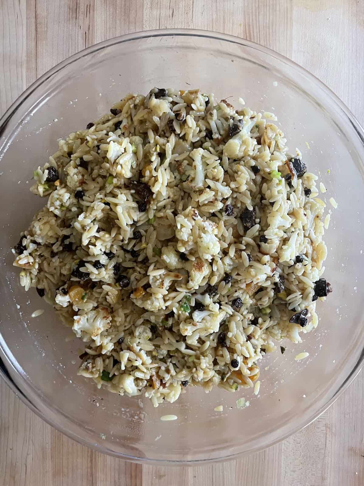 Orzo Salad with Roasted Cauliflower, Dried Fruit, and Pistachios in Citrus and Cumin Dressing -- all ingredients tossed together in a bowl