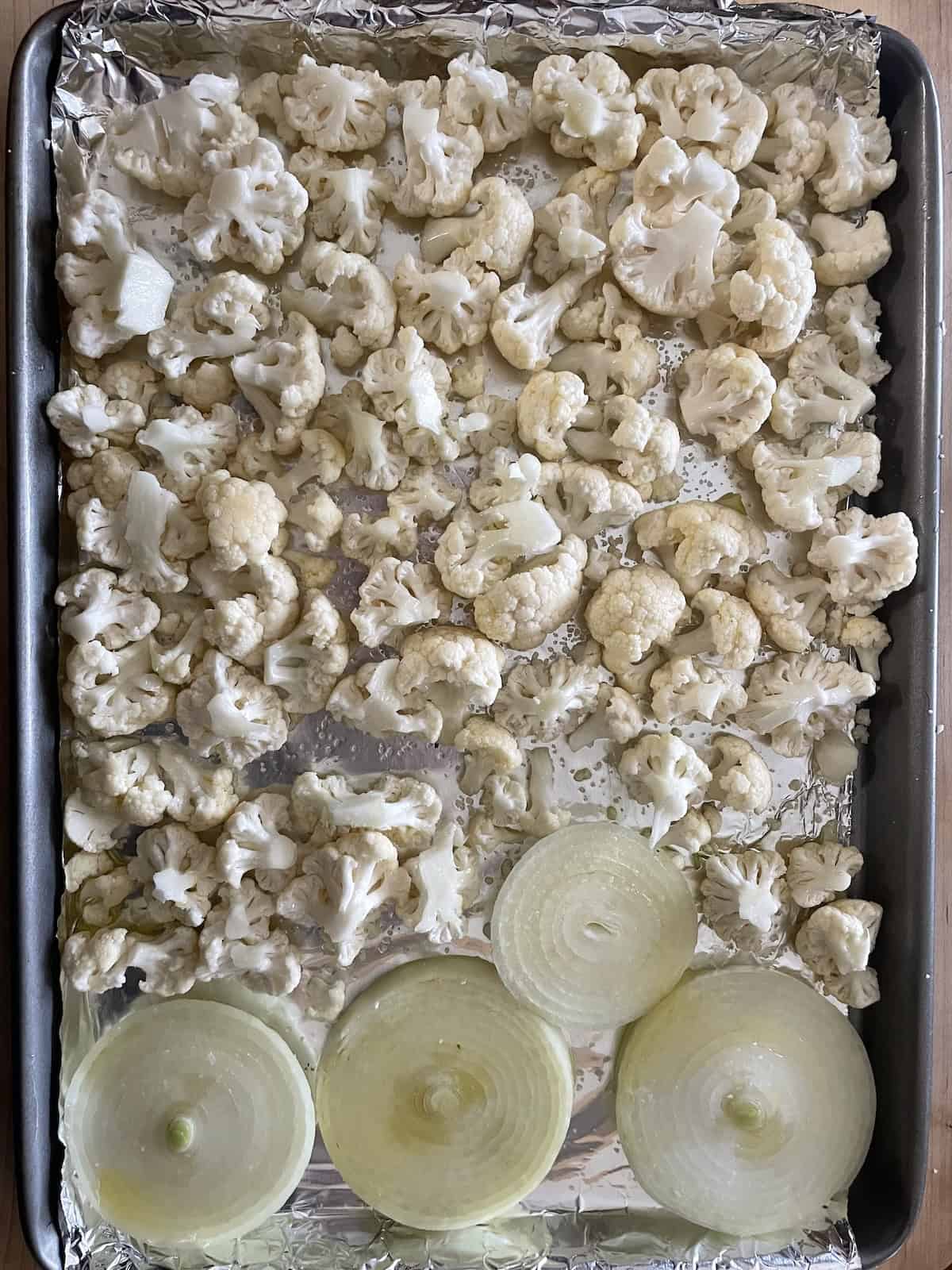 Orzo Salad with Roasted Cauliflower, Dried Fruit, and Pistachios in Citrus and Cumin Dressing -- cauliflower and onions on a baking sheet