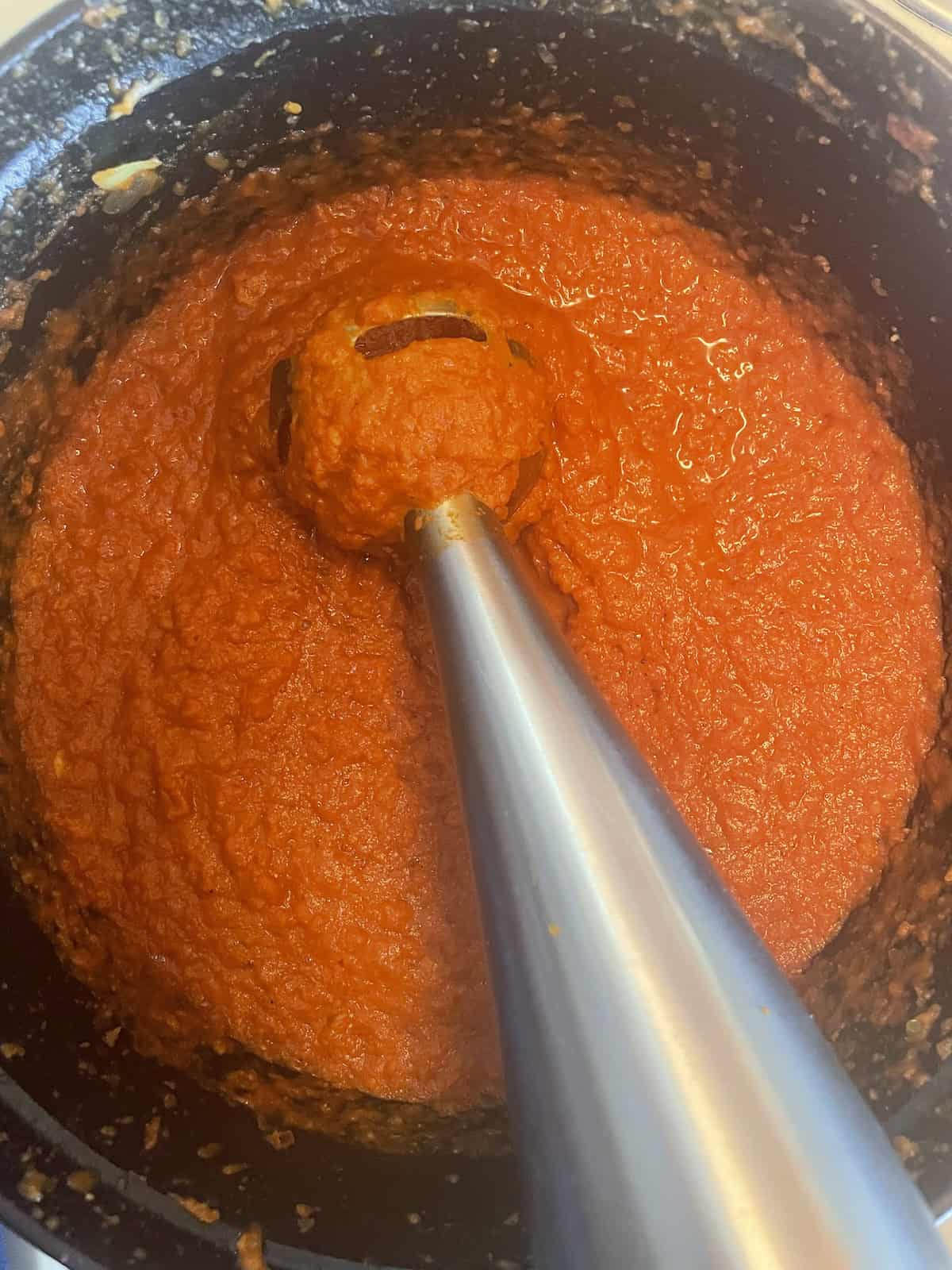 West African Peanut Soup with Chicken and Chickpeas blending with an immersion blender