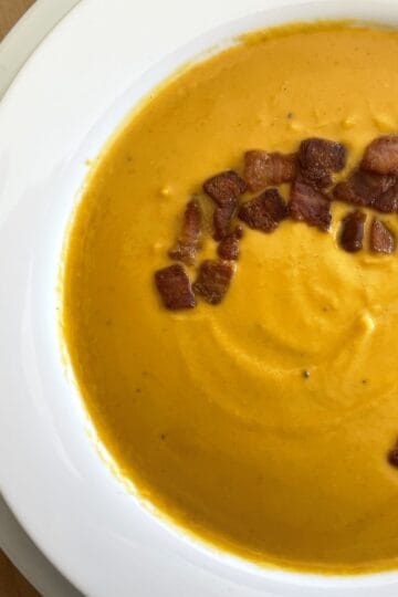 Butternut squash soup in bowl topped with bacon