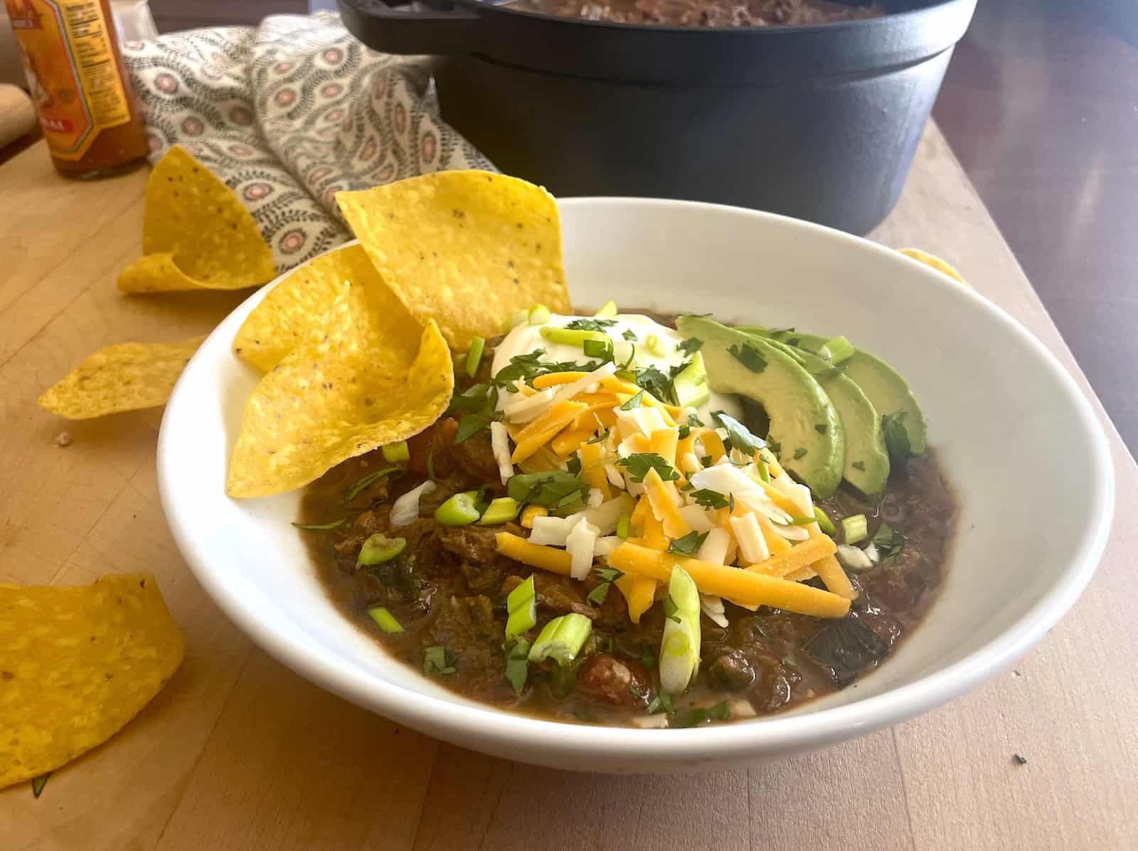 Slow Cooker Short Rib Mole Chili with Poblanos and Butternut Squash in a serving bowl with garnishes