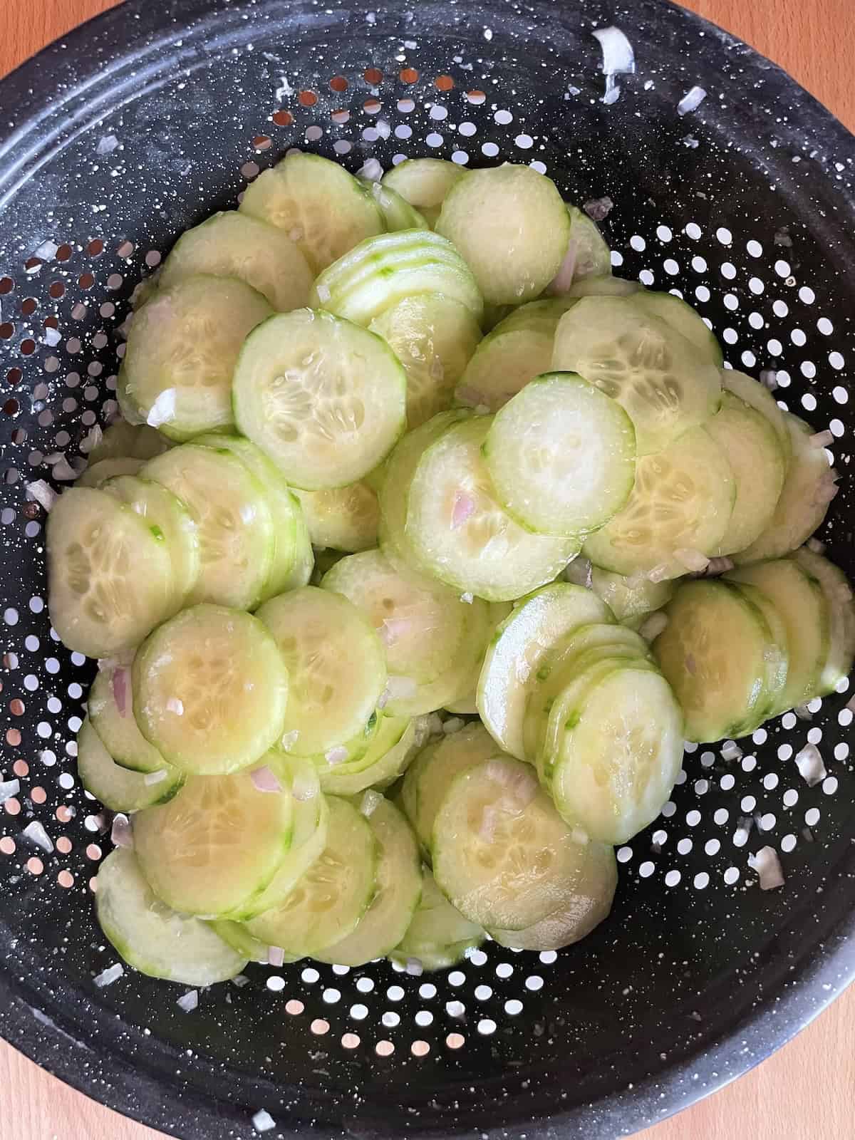 cucumbers and shallots in a colander tossed with salt