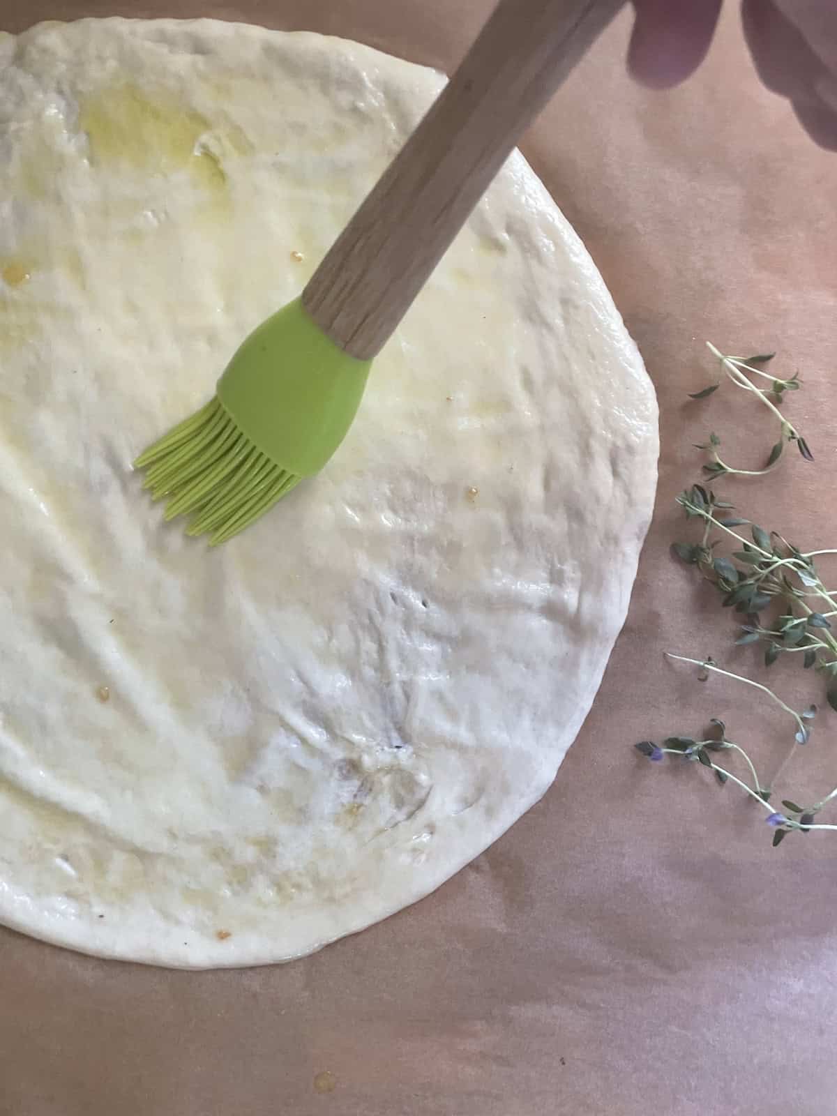 brushing pizza crust with olive oil