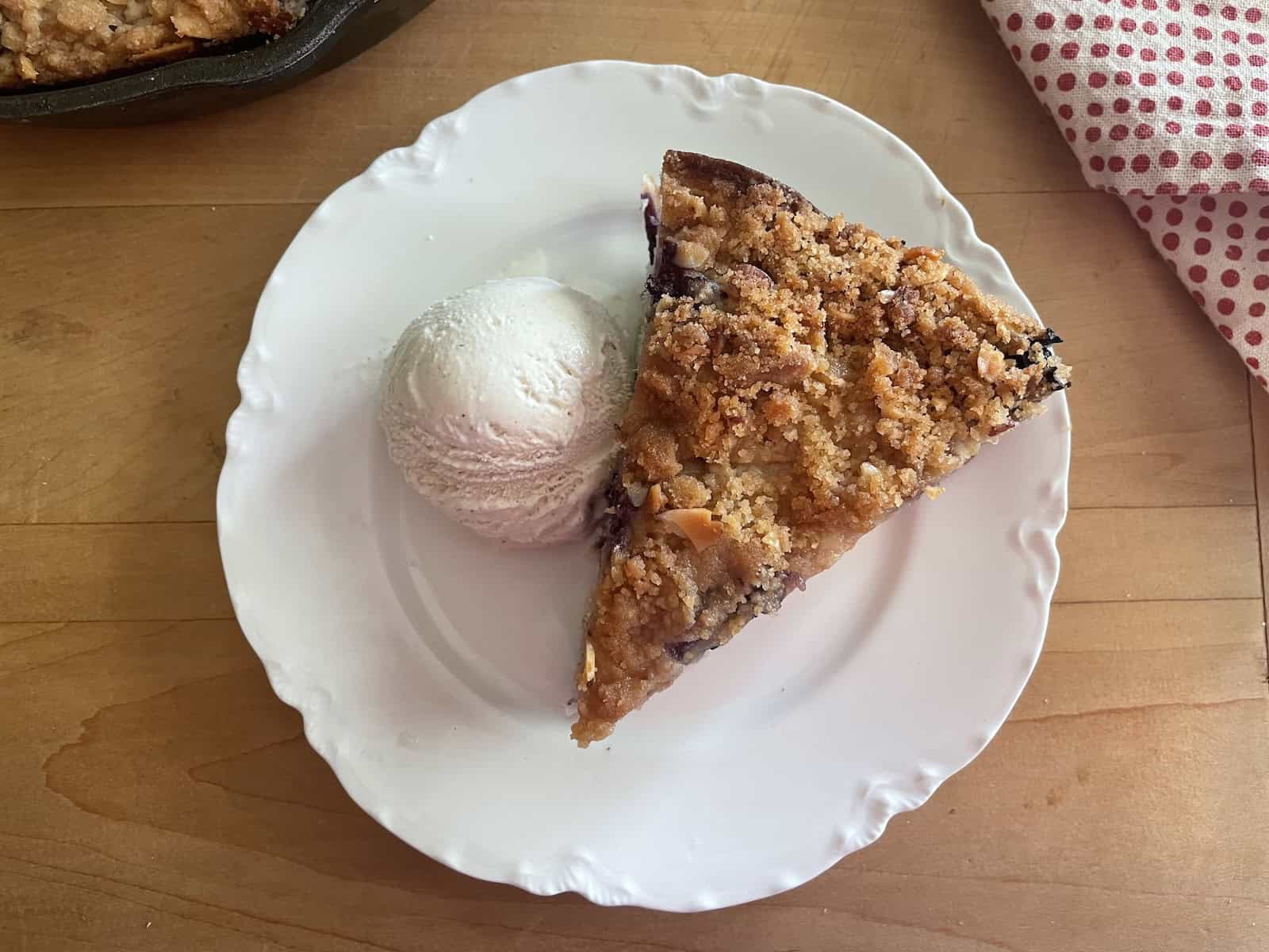 Peach and Blueberry Buttermilk Buckle with Almond Streusel slice on a plate with ice cream