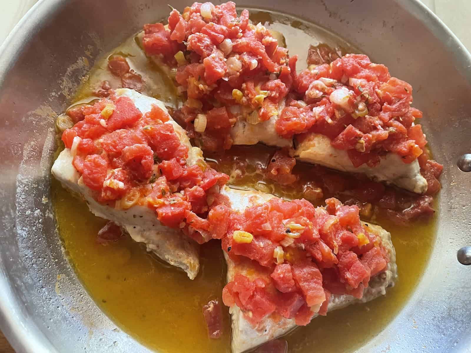 tomato topped red snapper in pan