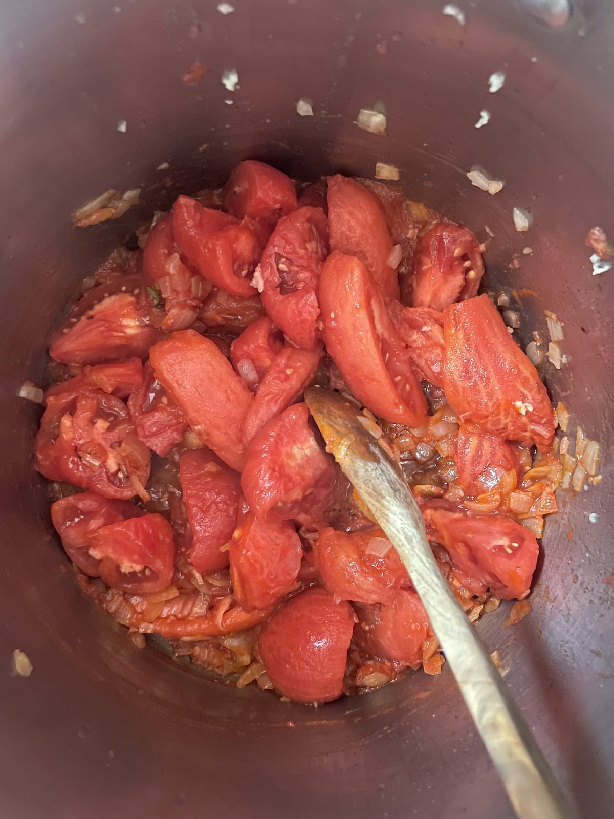adding tomatoes to soup pot