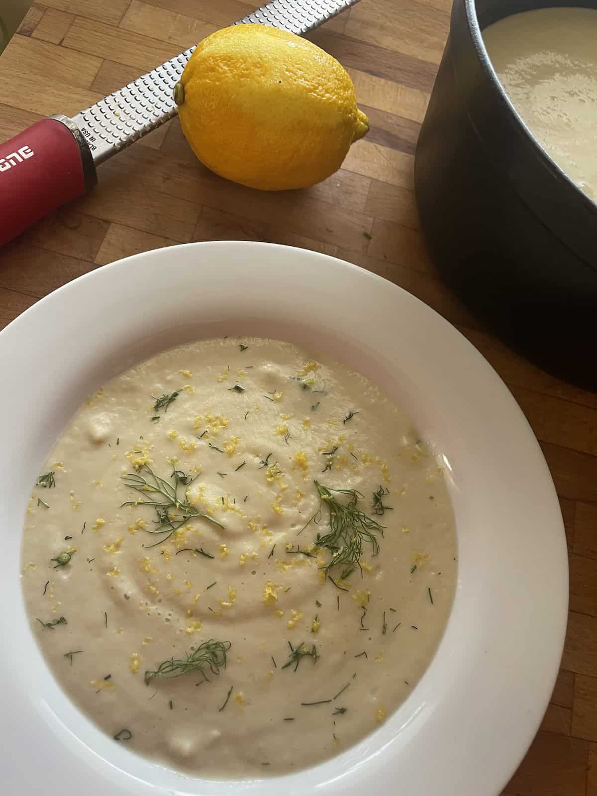 soup blended in bowl with fennel fronds and lemon zest