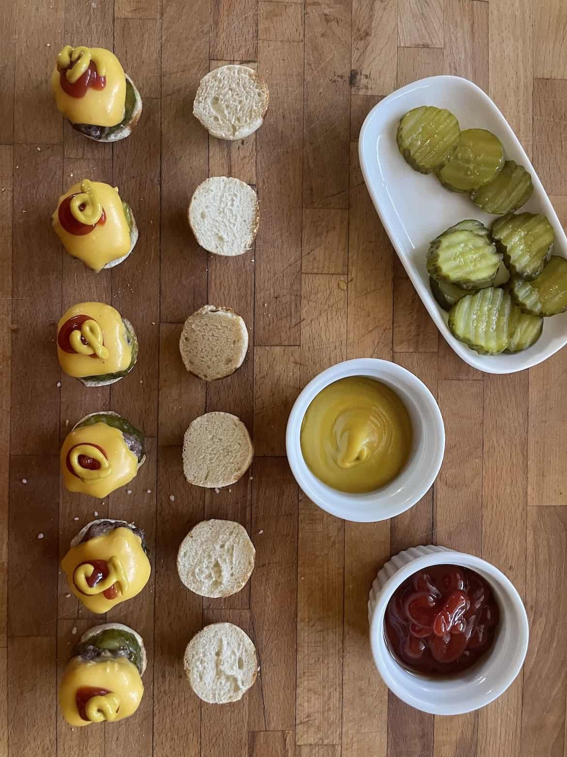 topping mini cheeseburger with ketchup and mustard